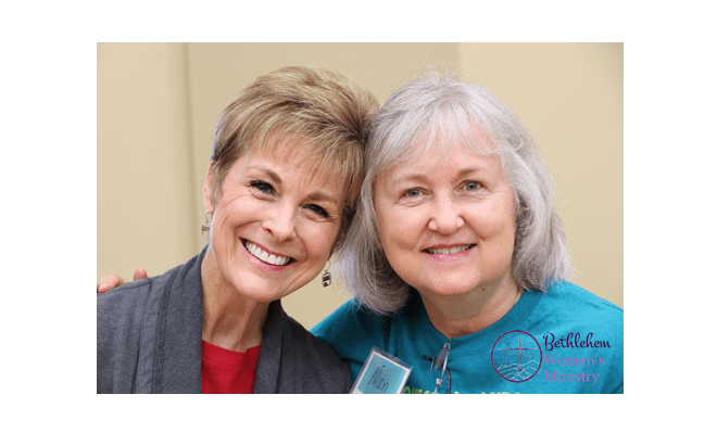 Two women with arms around each other and smiling with the Bethlehem Women's Ministry Logo in the bottom right corner.